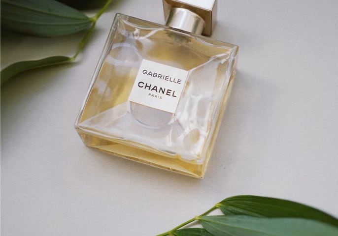 Bottle of perfume surrounded by green foliage